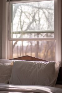 A serene bedroom with natural light streaming through an elegant window, creating a peaceful atmosphere.